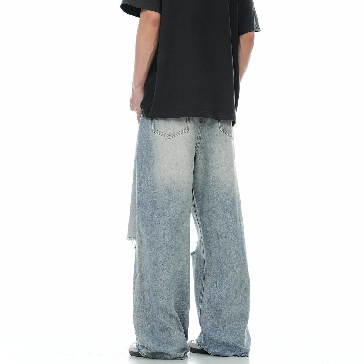 Blue men's straight-leg jeans with ripped distressing on the thigh, showing five-pocket design and zip fly.