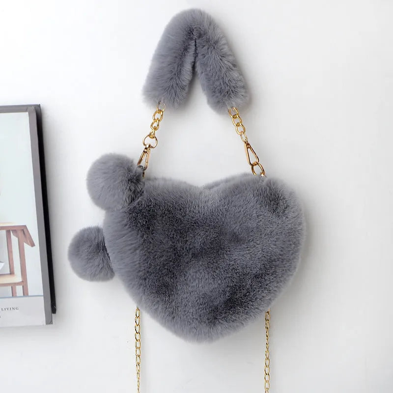 A soft, heart-shaped plush handbag for women in a medium size with a detachable shoulder strap.