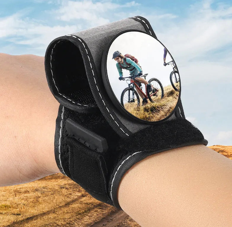 Black nylon wrist-mounted rear-view mirror for cyclists and motorcyclists on a textured background.