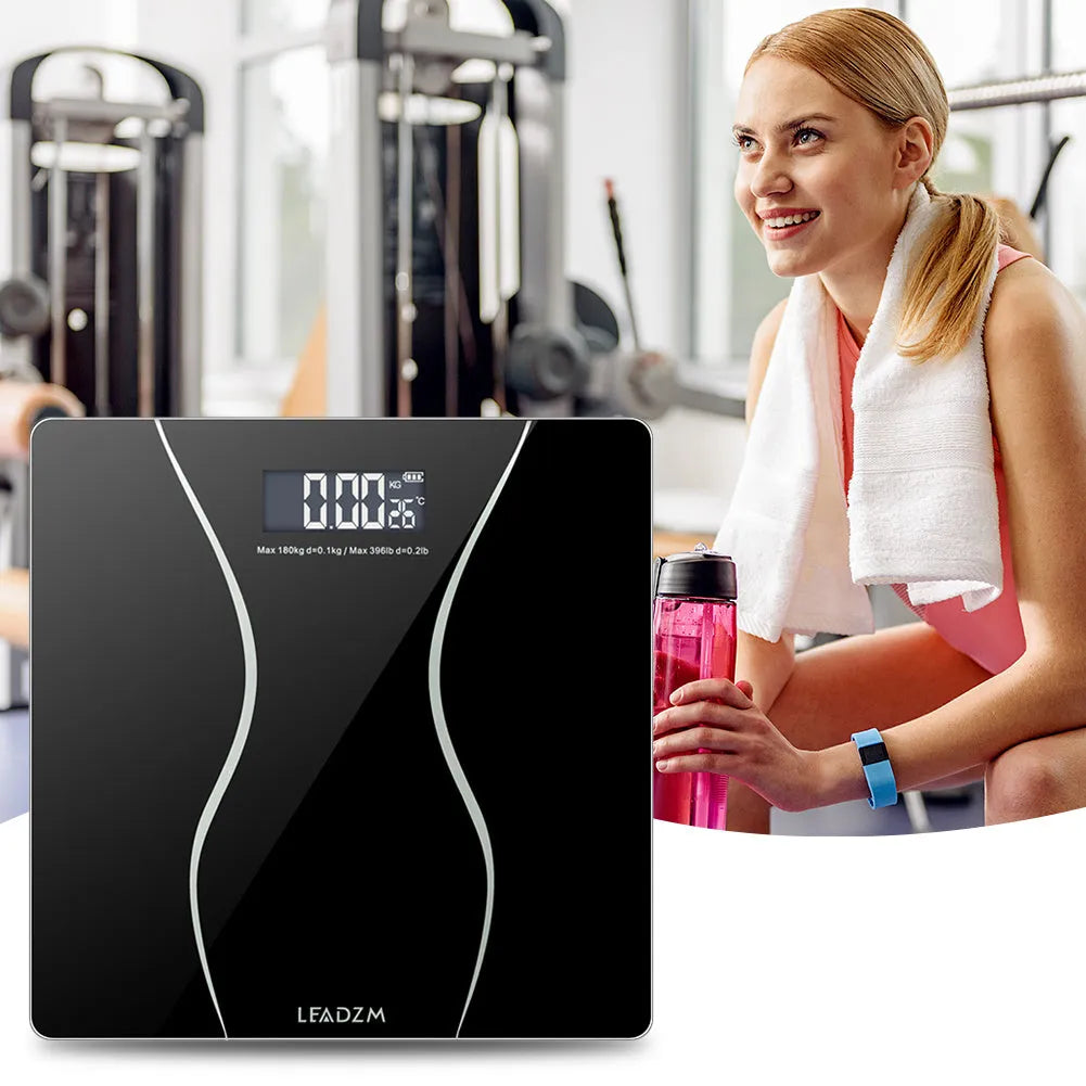 Black electronic digital bathroom scale on a bathroom floor, showing a maximum weight capacity of 180kg.