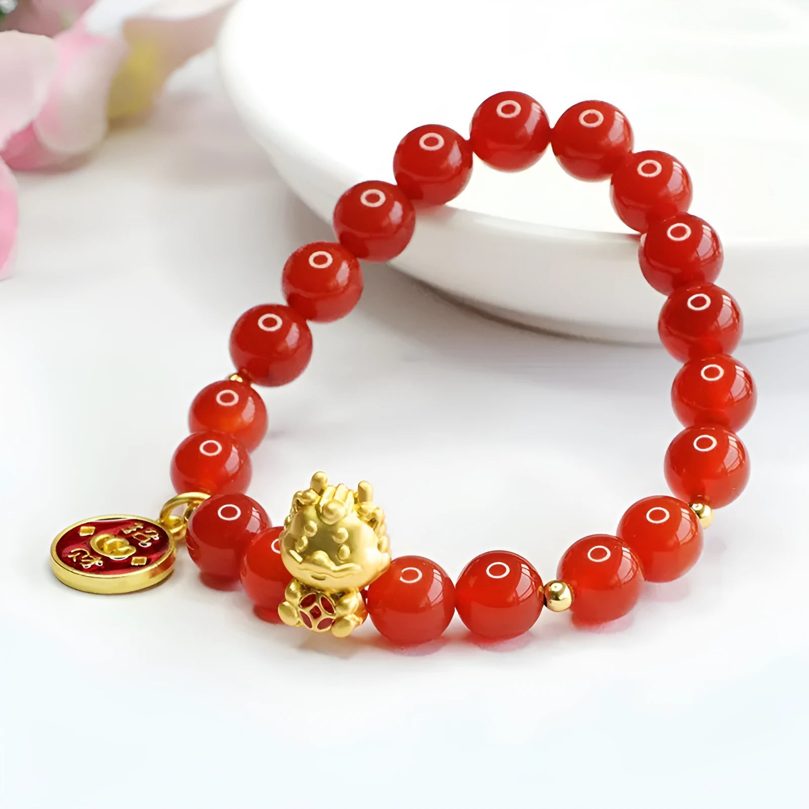 Close-up of a red agate beaded bracelet with a Chinese zodiac dragon charm on a wrist.