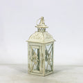 Black wrought iron floor lantern with glass panels on a stone patio.