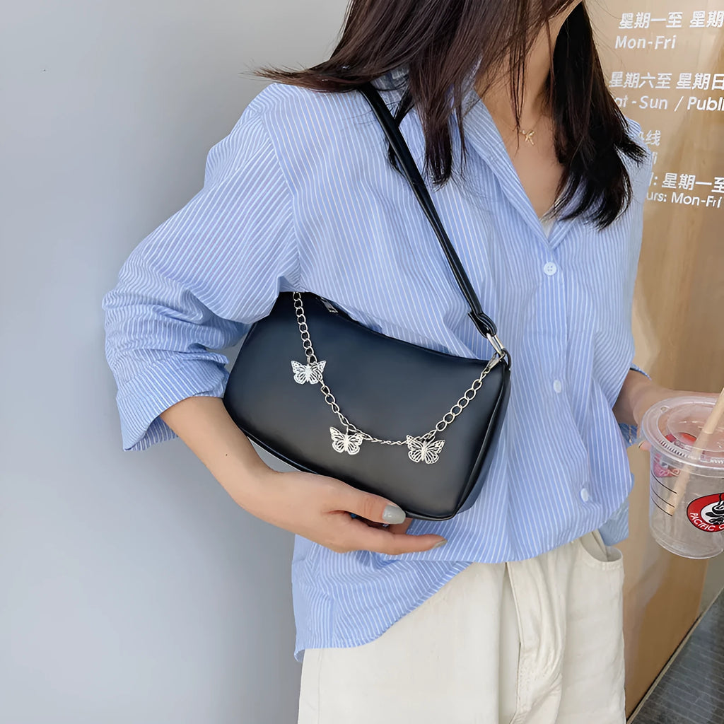 Women's black PU leather crossbody bag with butterfly chain shoulder strap showing internal phone pocket