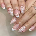 Short almond-shaped press-on nails with French manicure, flower patterns, and glitter accents in colour C625