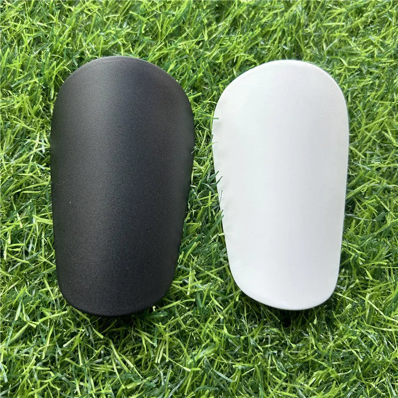 Extra small black and white plastic football shin guards for youth players, size 8cm by 5cm.