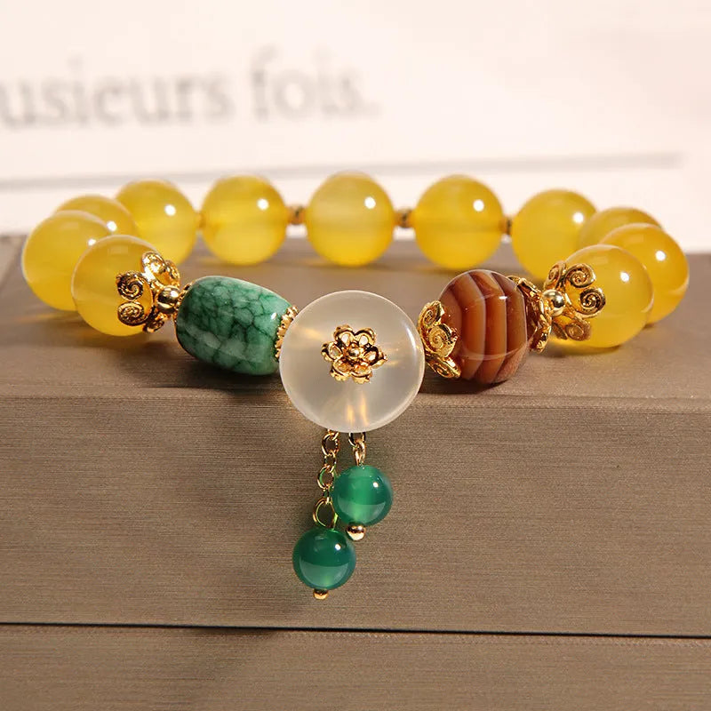 Yellow agate crystal bracelet with gold silk adjustable cord on a wrist, showing khaki coloured beads.