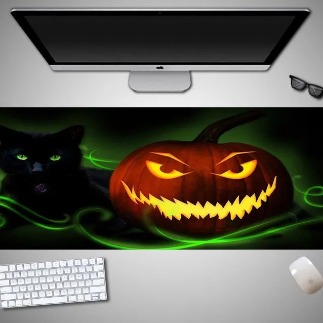 Oversized black Halloween-themed mouse pad with spooky artwork on a desk next to a gaming mouse.