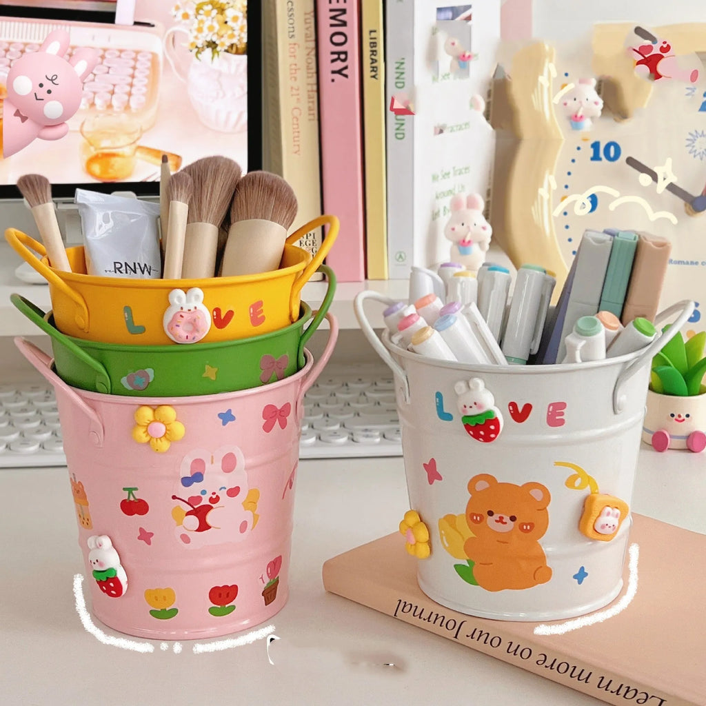 Round metal pen holder in a choice of colours including pink, green, red, white and yellow on a desk.