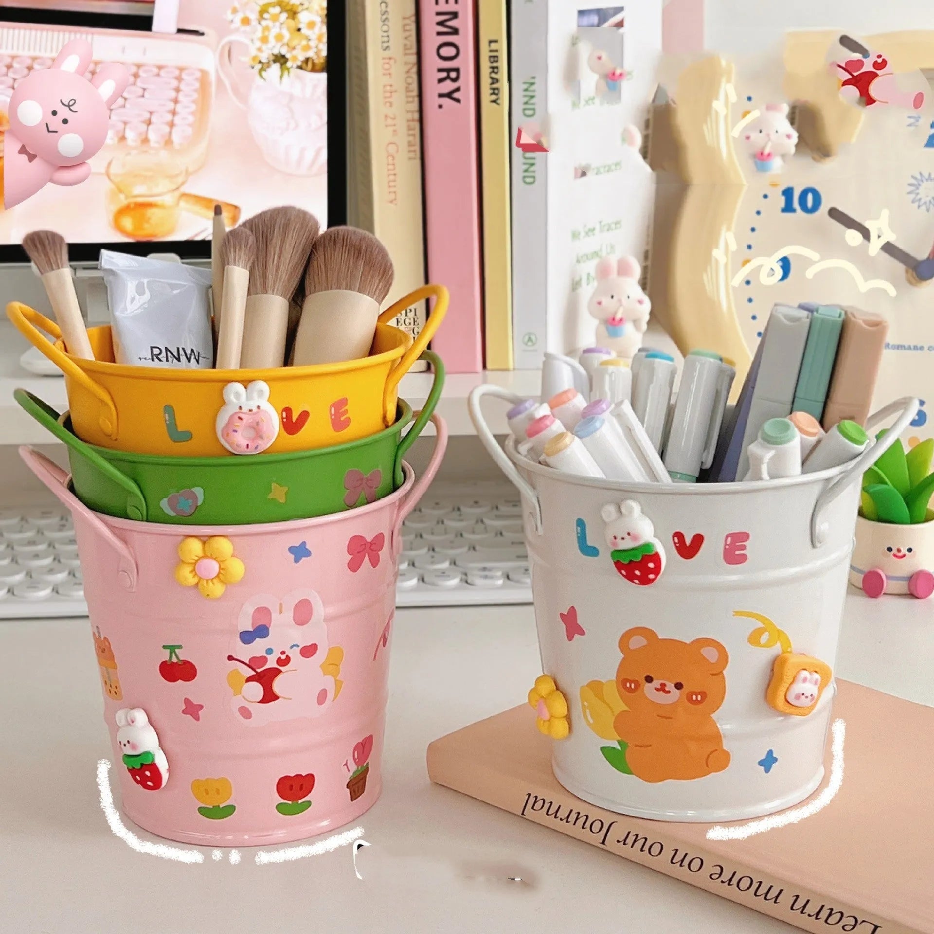 Round metal pen holder in a choice of colours including pink, green, red, white and yellow on a desk.
