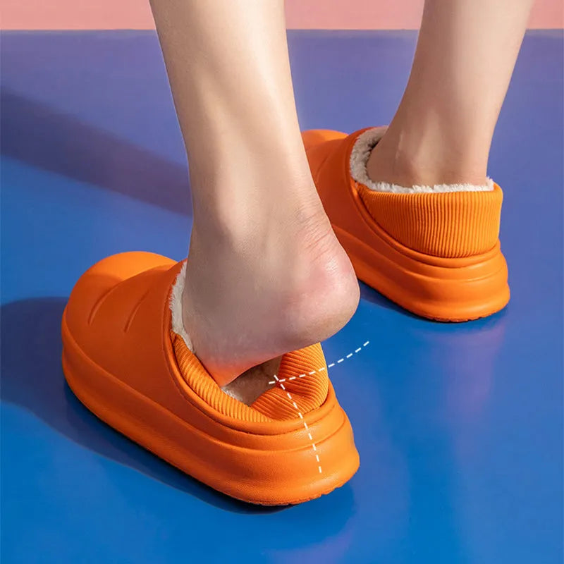 Green waterproof EVA garden slippers with plush lining and a non-slip sole, shown on a wooden deck.