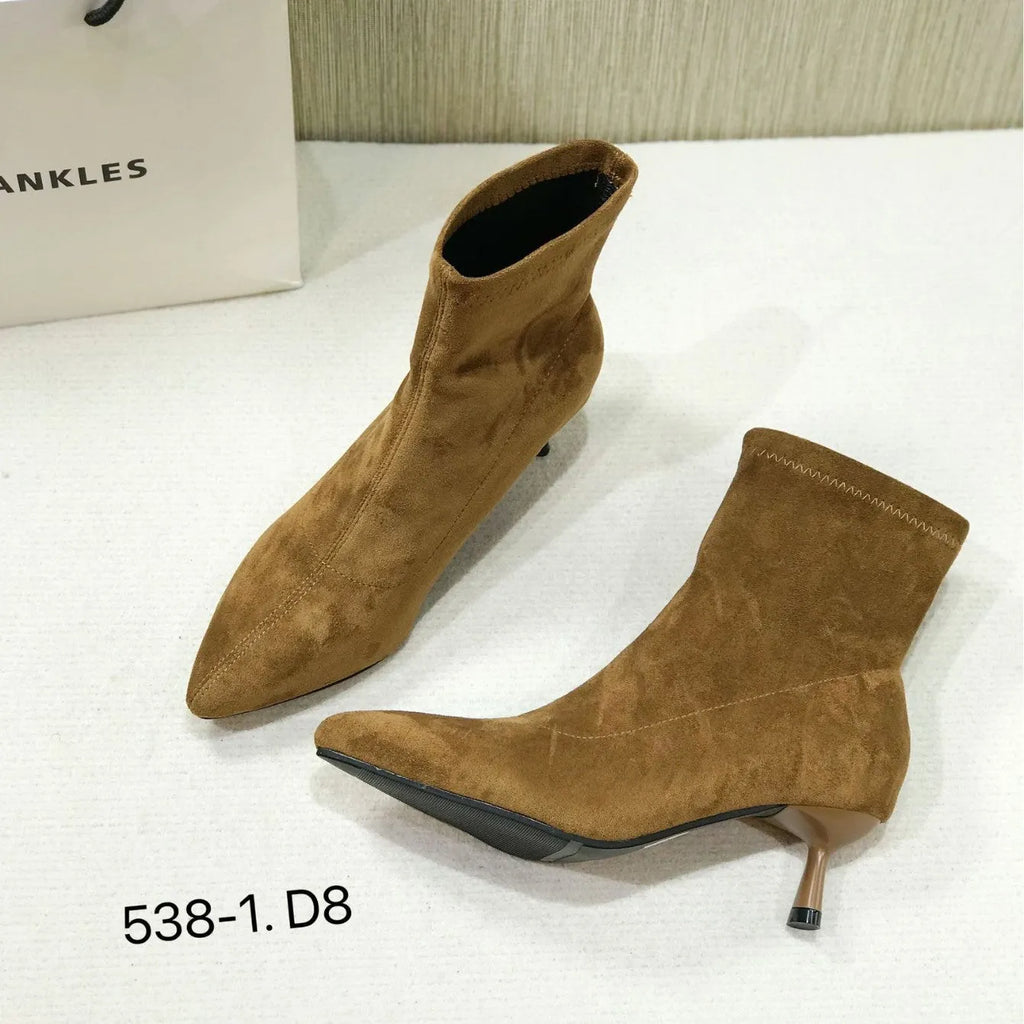Black pointed toe women's ankle boots with a high stiletto heel on a rubber sole.