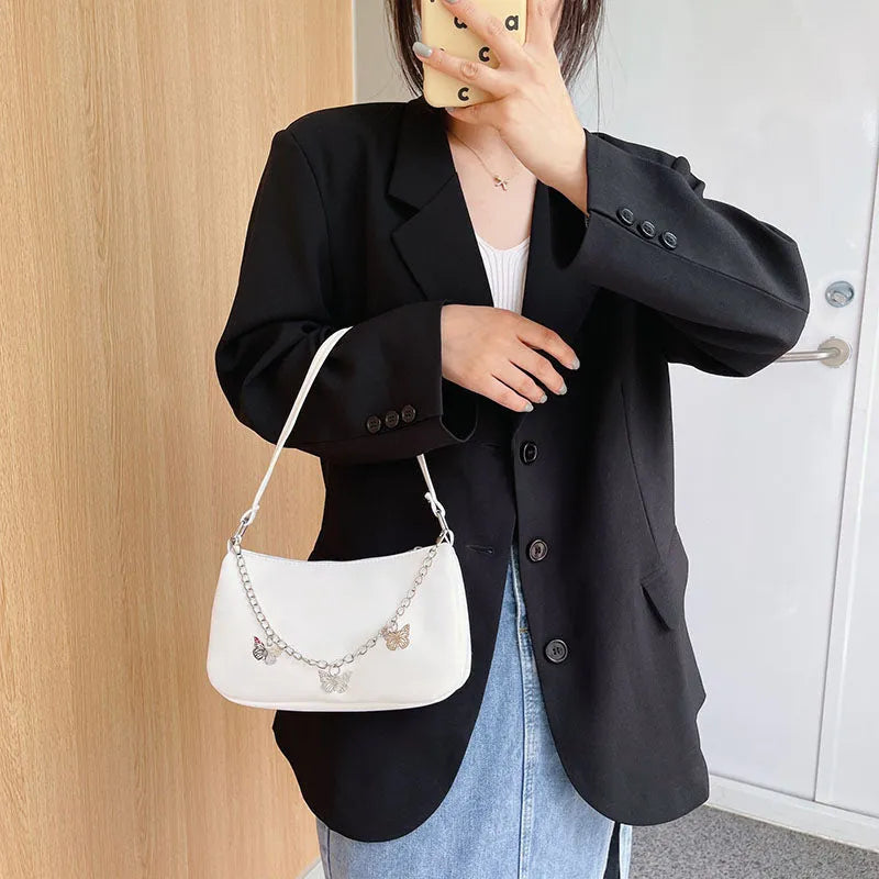 Women's black PU leather crossbody bag with butterfly chain shoulder strap showing internal phone pocket