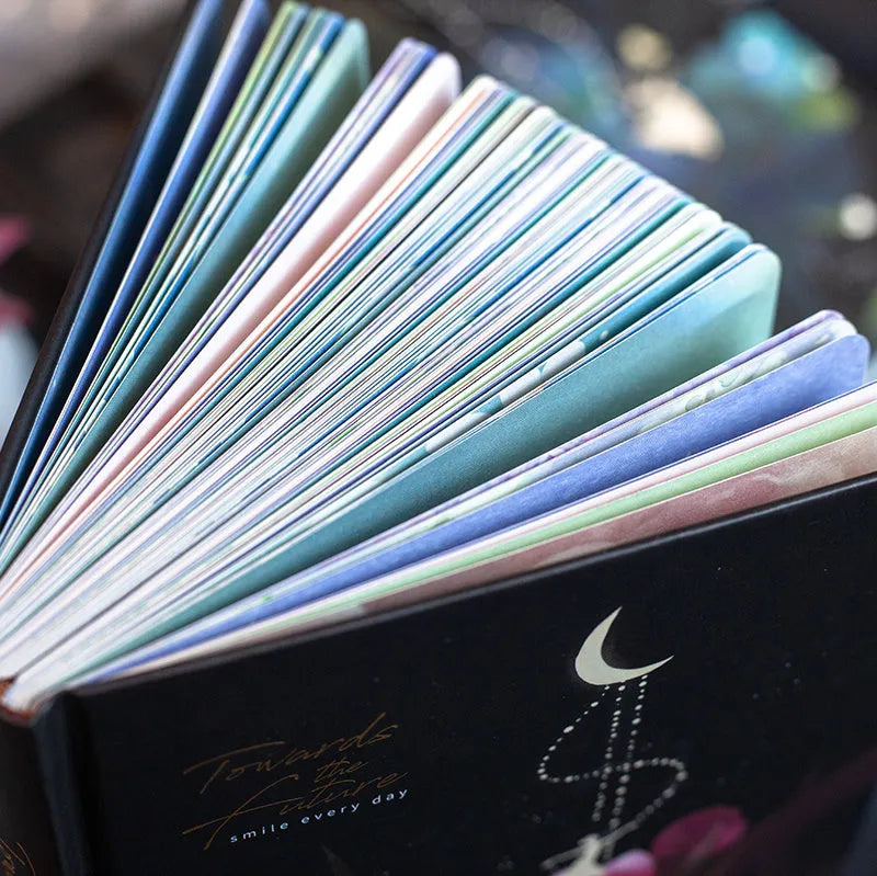 A5 notebook with luminous cover in deep blue, open to show lined pages with colour illustrations.