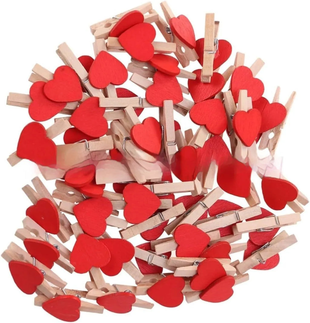 Five handmade solid wood heart-shaped clips in red, white, and pink on a wooden surface.