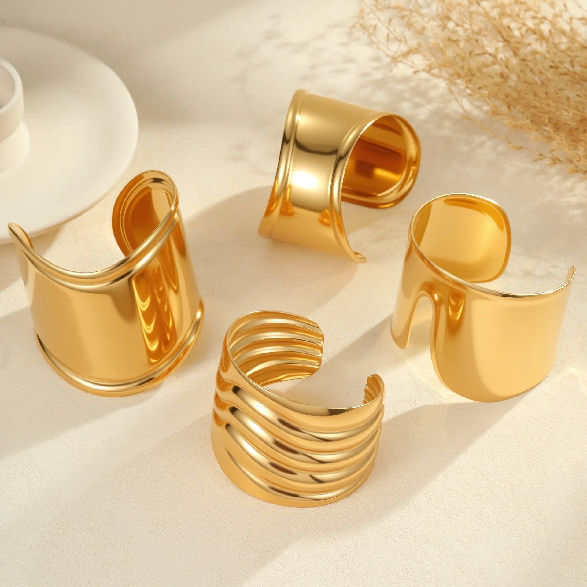 Women's wide stainless steel bracelet with 18K gold plating, geometric wave design, and niche opening closure.