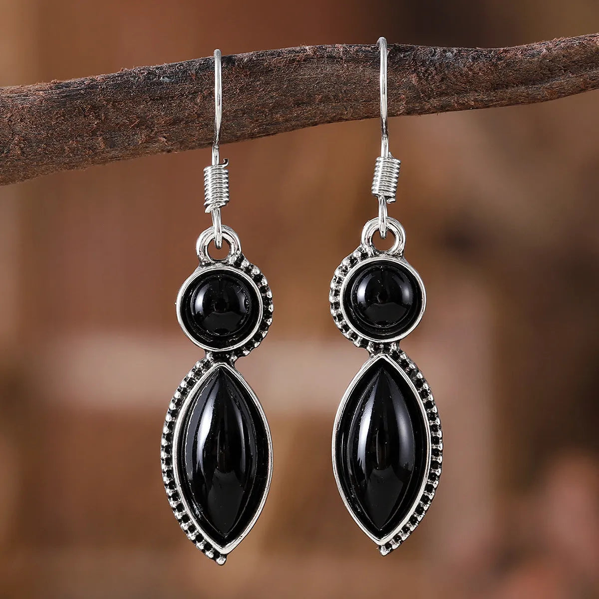 A pair of geometric vintage earrings with a black and purple electroplated finish, showing a pendant design with round elements.