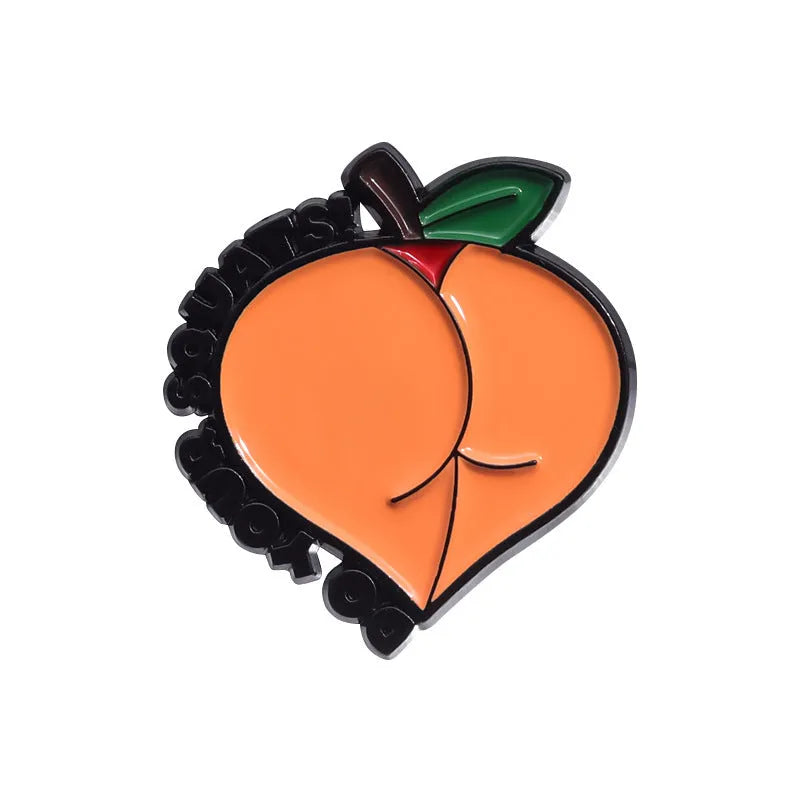 Colourful metal brooch with cartoon fruit and letter design on a blue background.