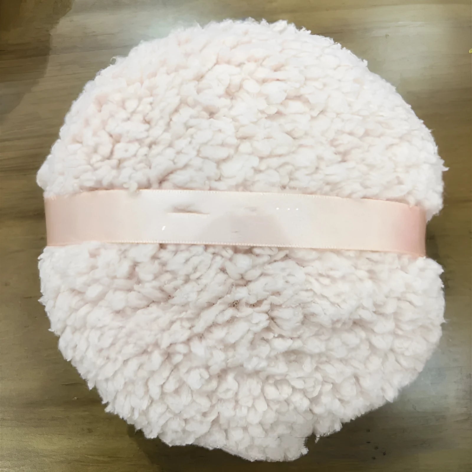Oversized rectangular plush powder puff in white on a pink background.