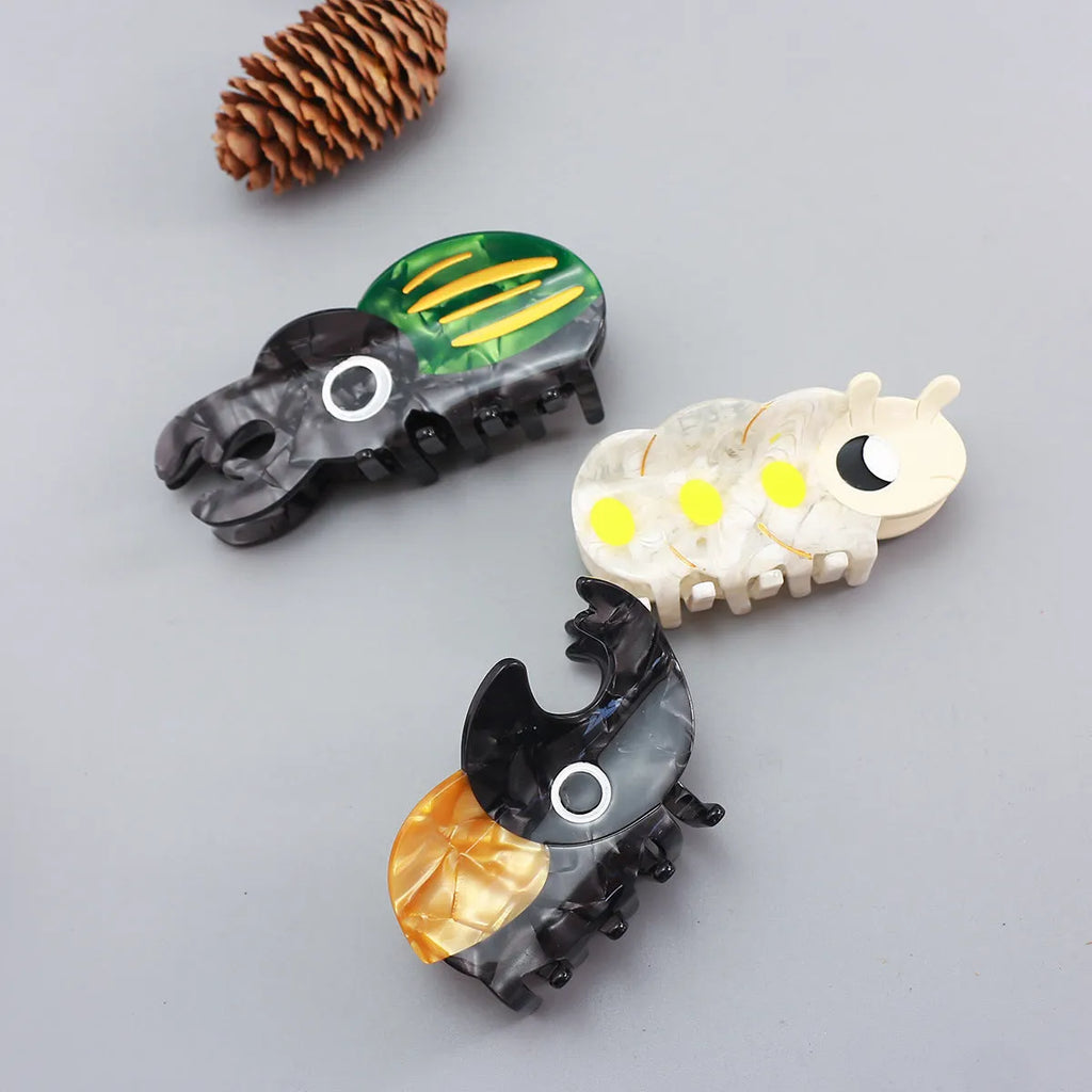 Handmade cellulose acetate insect grip with green beetle, orange beetle, and white caterpillar models for biology study.