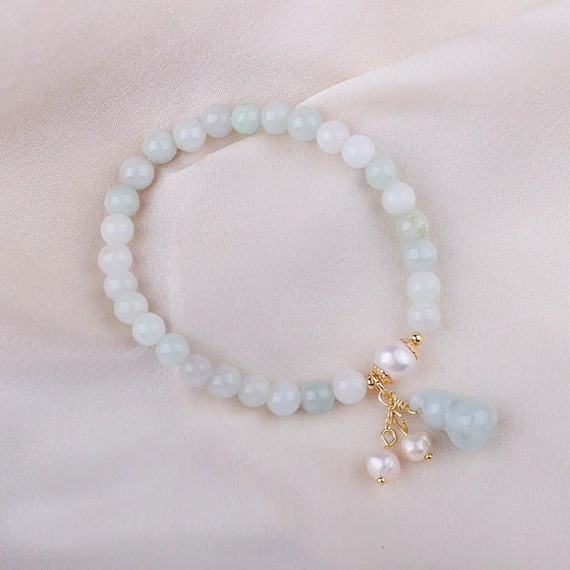 Close-up of a natural emerald jade bracelet with a detailed pearl jade gourd charm pendant.