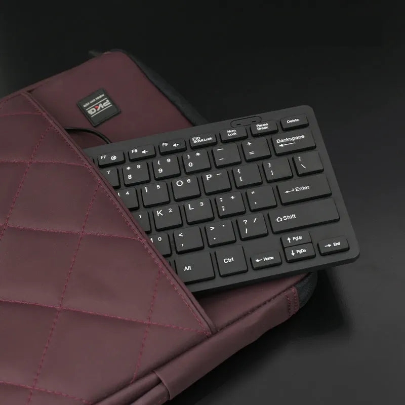 Compact USB wired mini keyboard in black, white, pink, or blue on a desk.