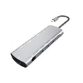 Grey aluminium USB-C docking station with HDMI, VGA, USB, and charging ports on a desk.