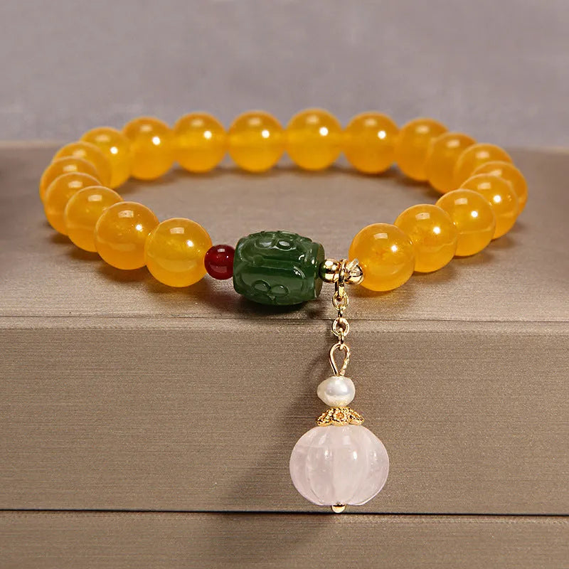 Yellow agate crystal bracelet with gold silk adjustable cord on a wrist, showing khaki coloured beads.