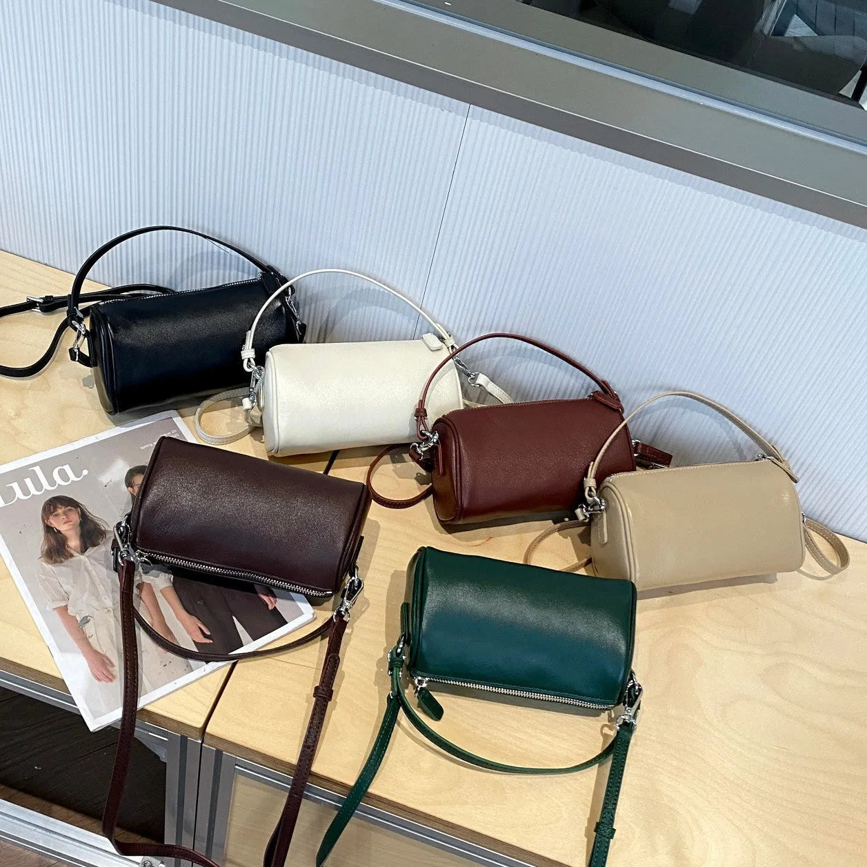 Soft genuine leather cylindrical crossbody phone bag in brown with a single shoulder strap.
