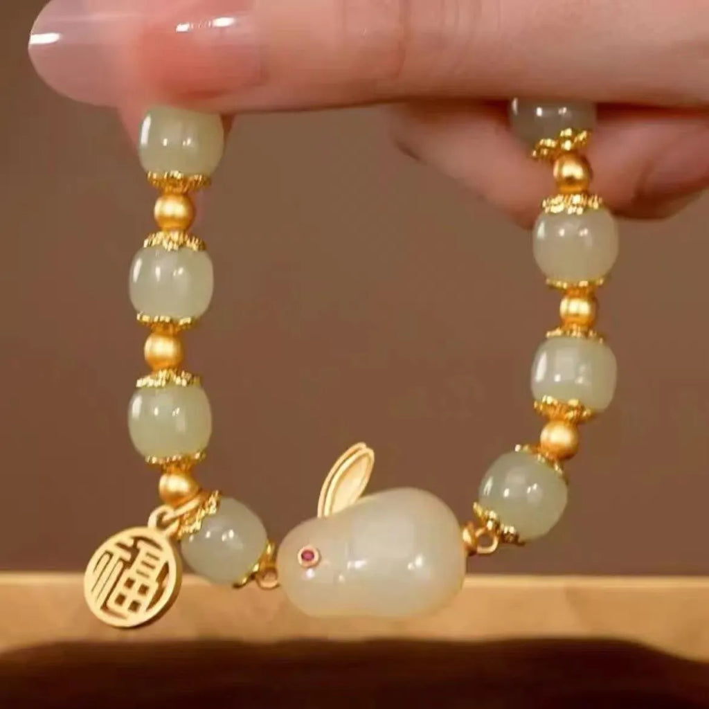 Green jade lucky bracelet with black hare charm, fu character, and lily flower on black adjustable cord.