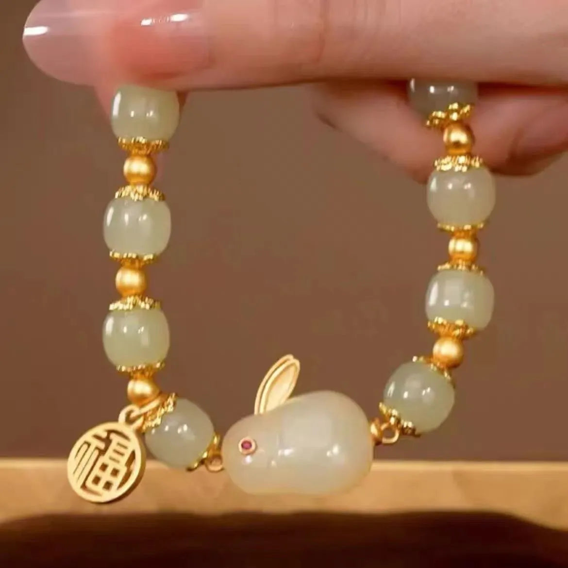Green jade lucky bracelet with black hare charm, fu character, and lily flower on black adjustable cord.
