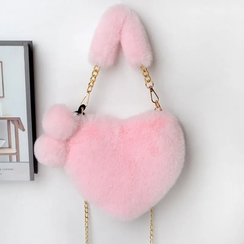 A soft, heart-shaped plush handbag for women in a medium size with a detachable shoulder strap.