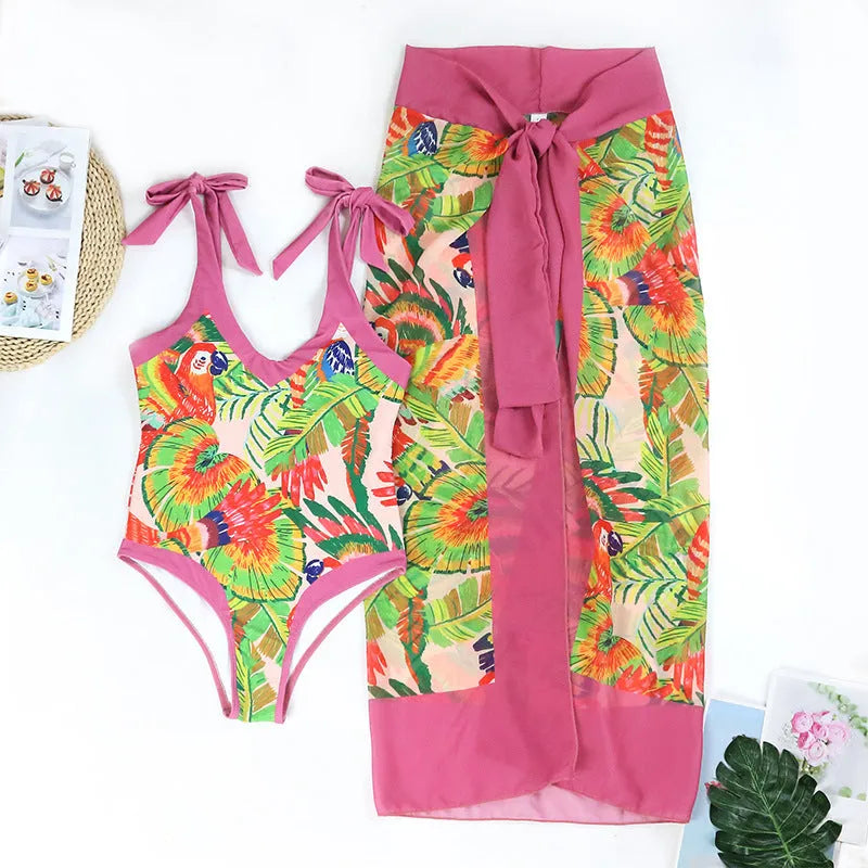 Pink floral print women's one-piece swimsuit with V-neck and matching skirt on beach