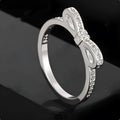 Silver coloured bow-shaped ring with zircon crystal details on a white background.