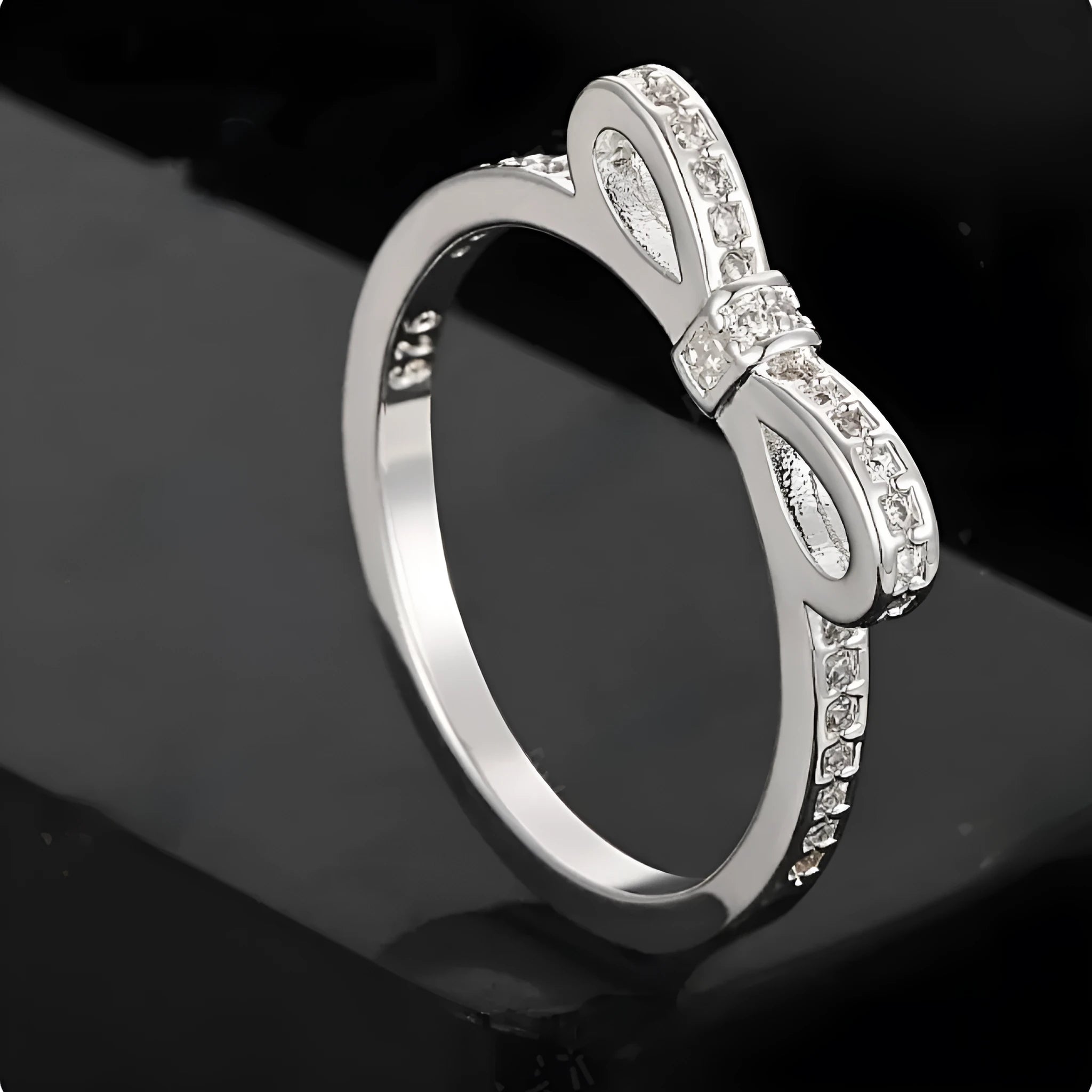 Silver coloured bow-shaped ring with zircon crystal details on a white background.