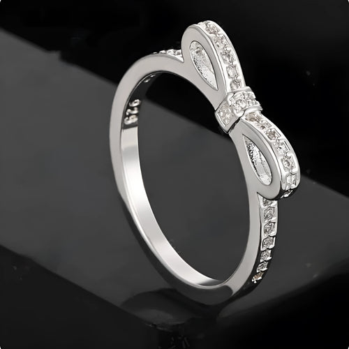Silver coloured bow-shaped ring with zircon crystal details on a white background.