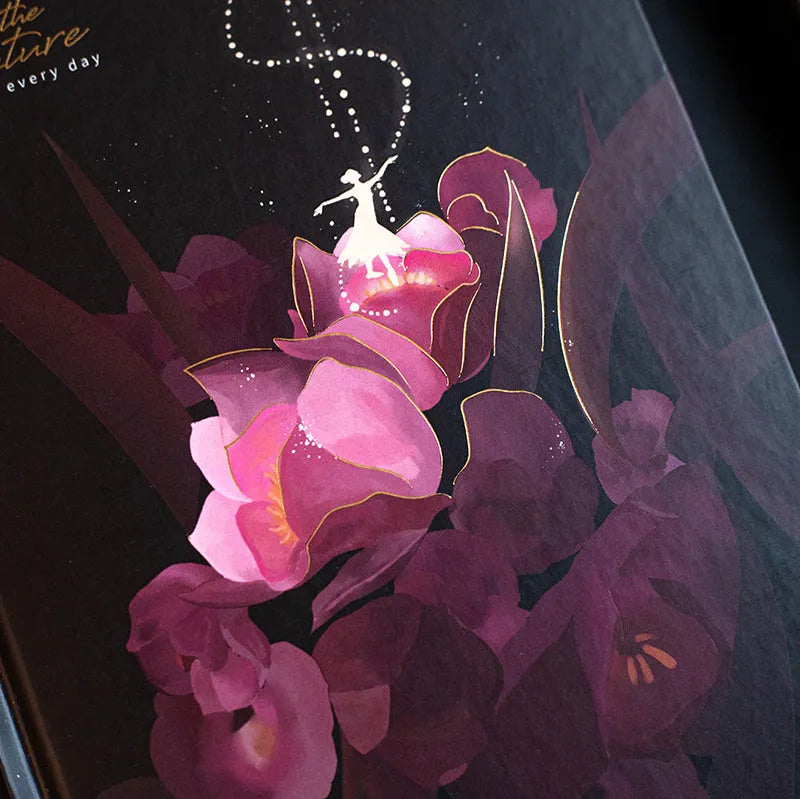 A5 notebook with luminous cover in deep blue, open to show lined pages with colour illustrations.