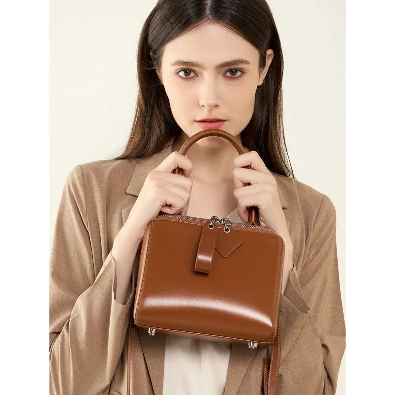 Open grain leather handbag in black with visible grain texture and welt pocket on front