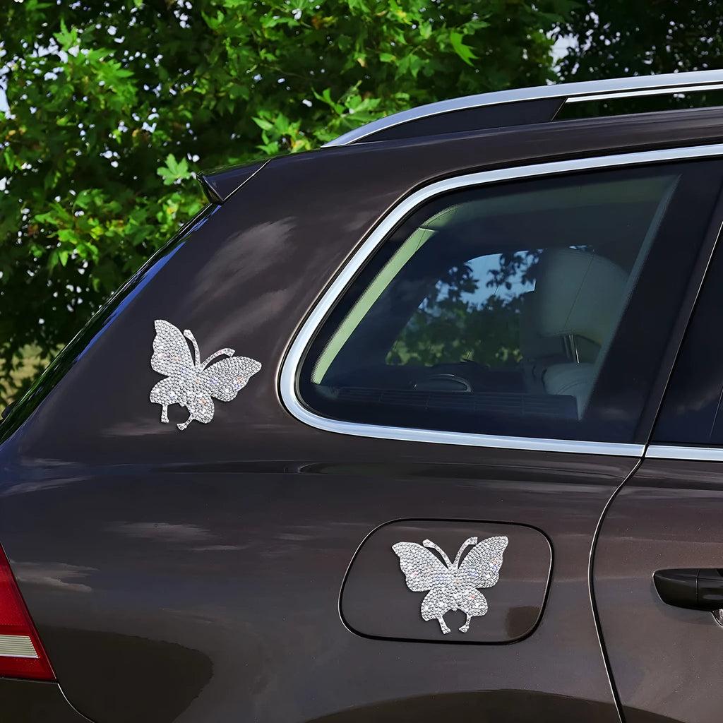 Close-up of a diamond-sparkle glass car sticker in a butterfly or bear paw design on a car surface.