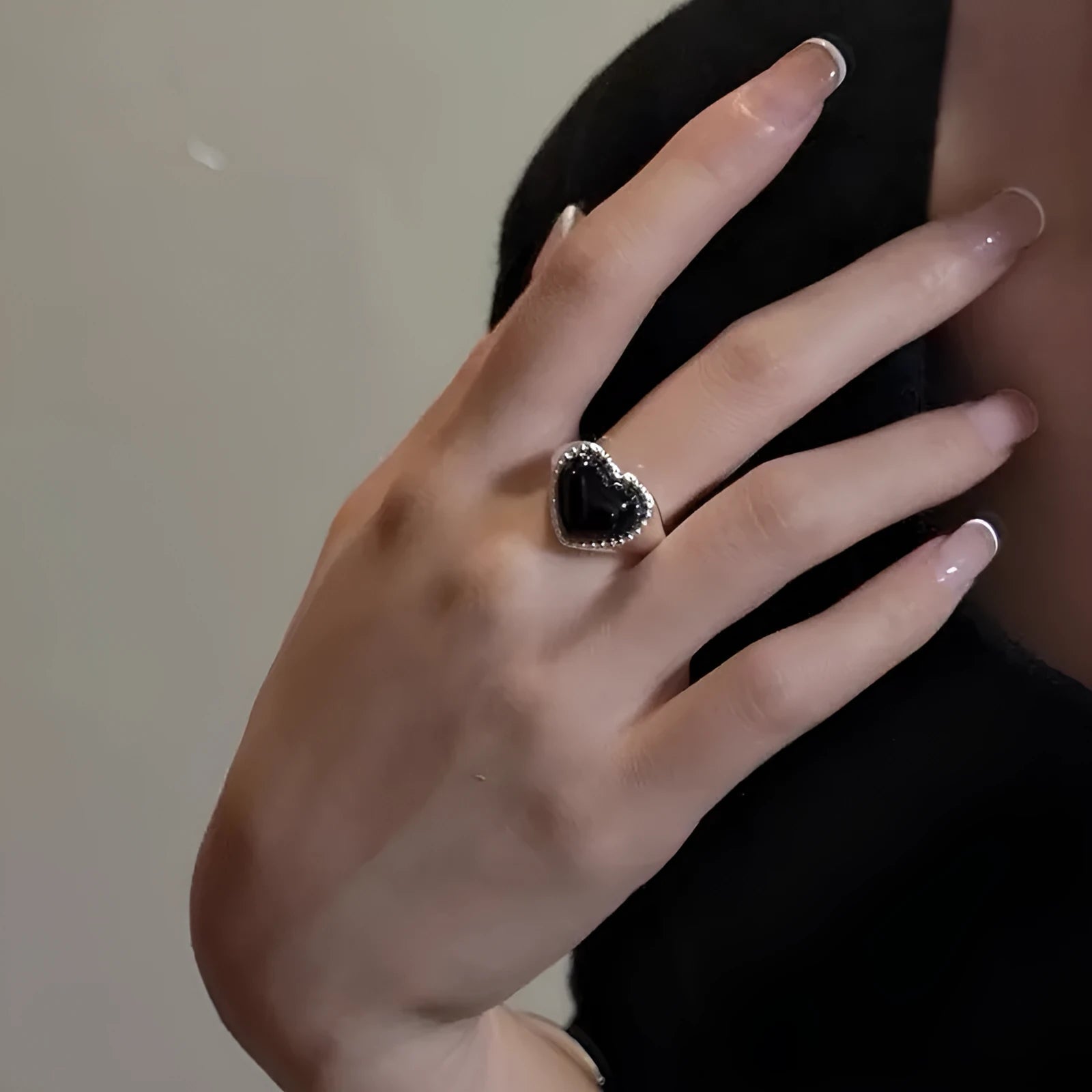 S925 sterling silver adjustable ring with a black agate heart design on a finger.