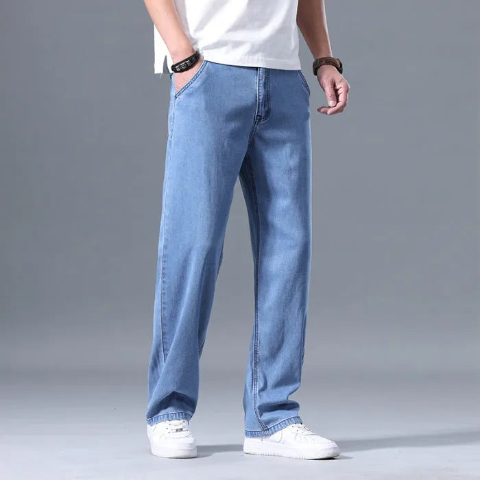 Man wearing light blue loose straight-leg lyocell jeans on a casual background.