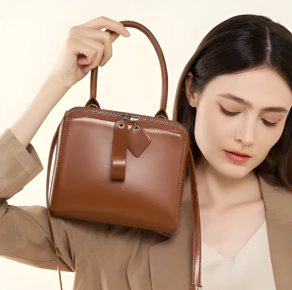Open grain leather handbag in black with visible grain texture and welt pocket on front