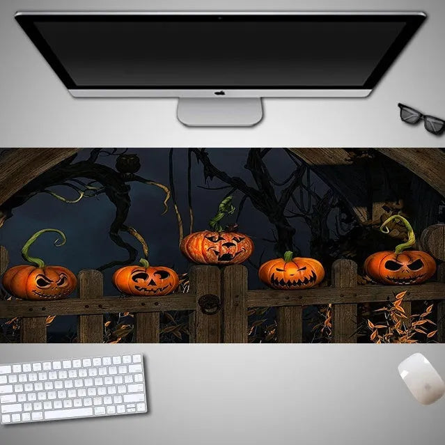 Oversized black Halloween-themed mouse pad with spooky artwork on a desk next to a gaming mouse.