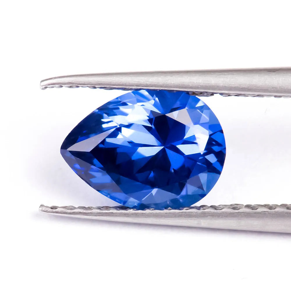Royal blue loose gemstone in heart, round, and pear shapes on a white background.