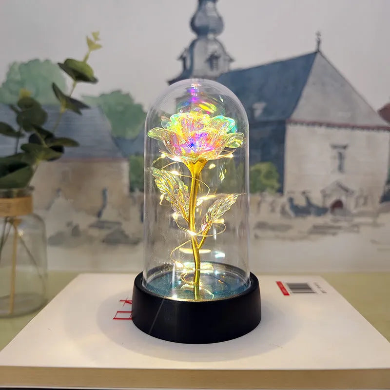 Small decorative table lamp with coloured LED lights illuminating plastic flowers under a glass dome.