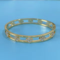 Gold and silver women's hollow bracelets with zircon stones and four-leaf clover charms on a white background.