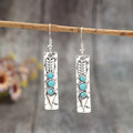 Geometric long silver earrings with blue turquoise inlay detail on a white background.