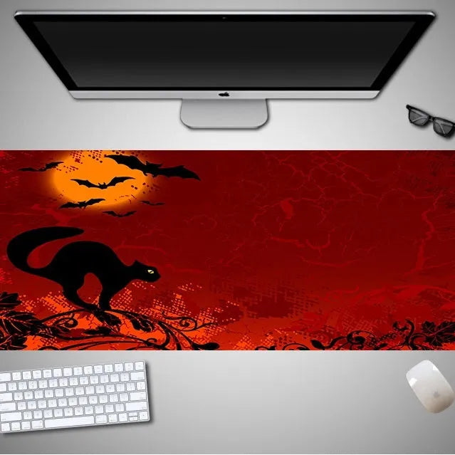 Oversized black Halloween-themed mouse pad with spooky artwork on a desk next to a gaming mouse.