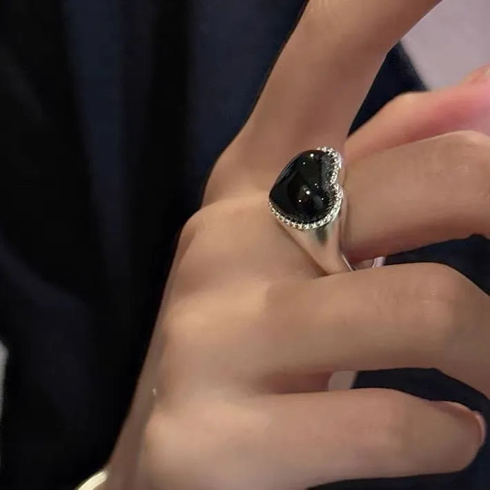 S925 sterling silver adjustable ring with a black agate heart design on a finger.