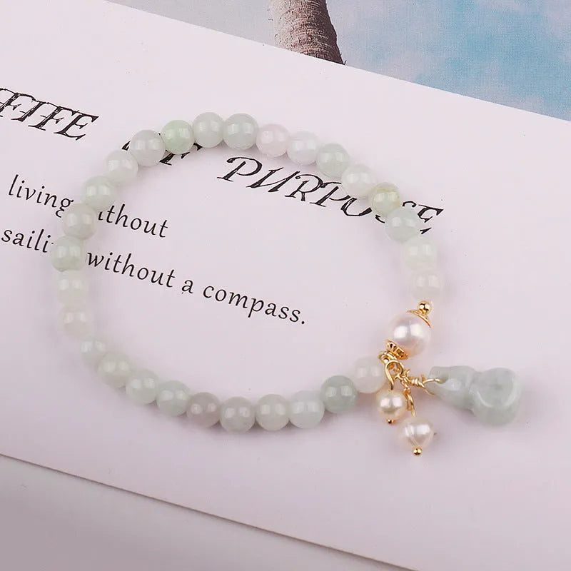 Close-up of a natural emerald jade bracelet with a detailed pearl jade gourd charm pendant.