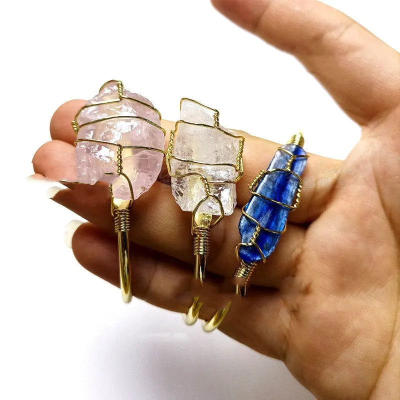 Geometric gold wire bracelet holding a rough natural crystal stone, bohemian style